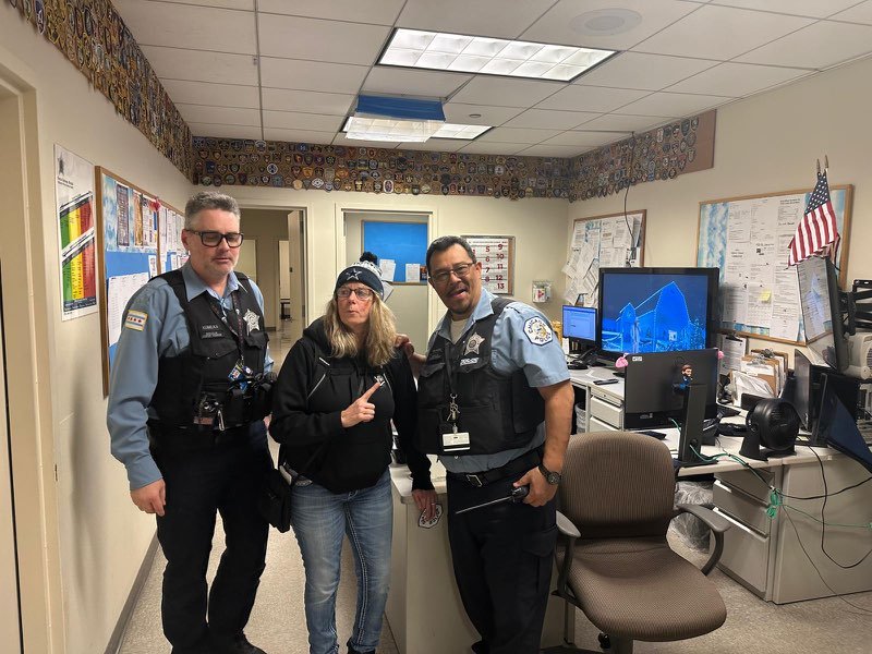 Two uniformed security officers standing with Michaella Franklin giving a thumbs-up inside a secure office environment with computers and an American flag
